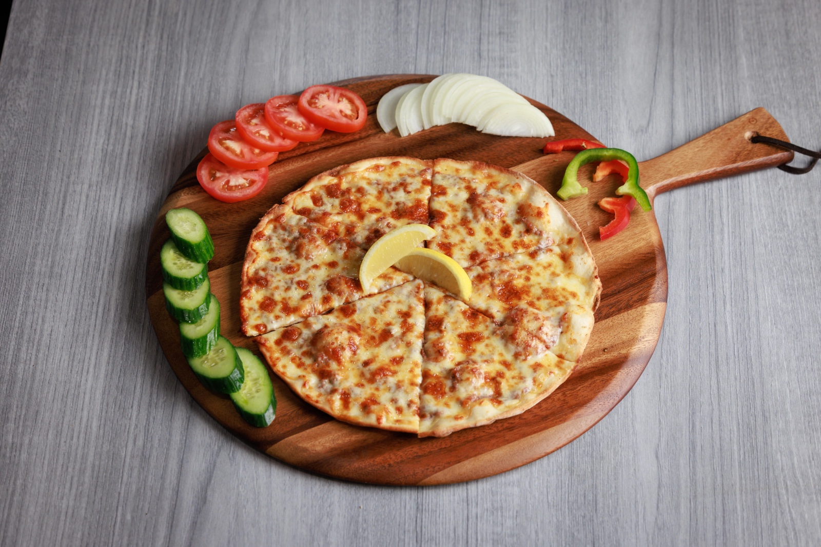 Sliced meat and cheese manoush on a wooden serving board